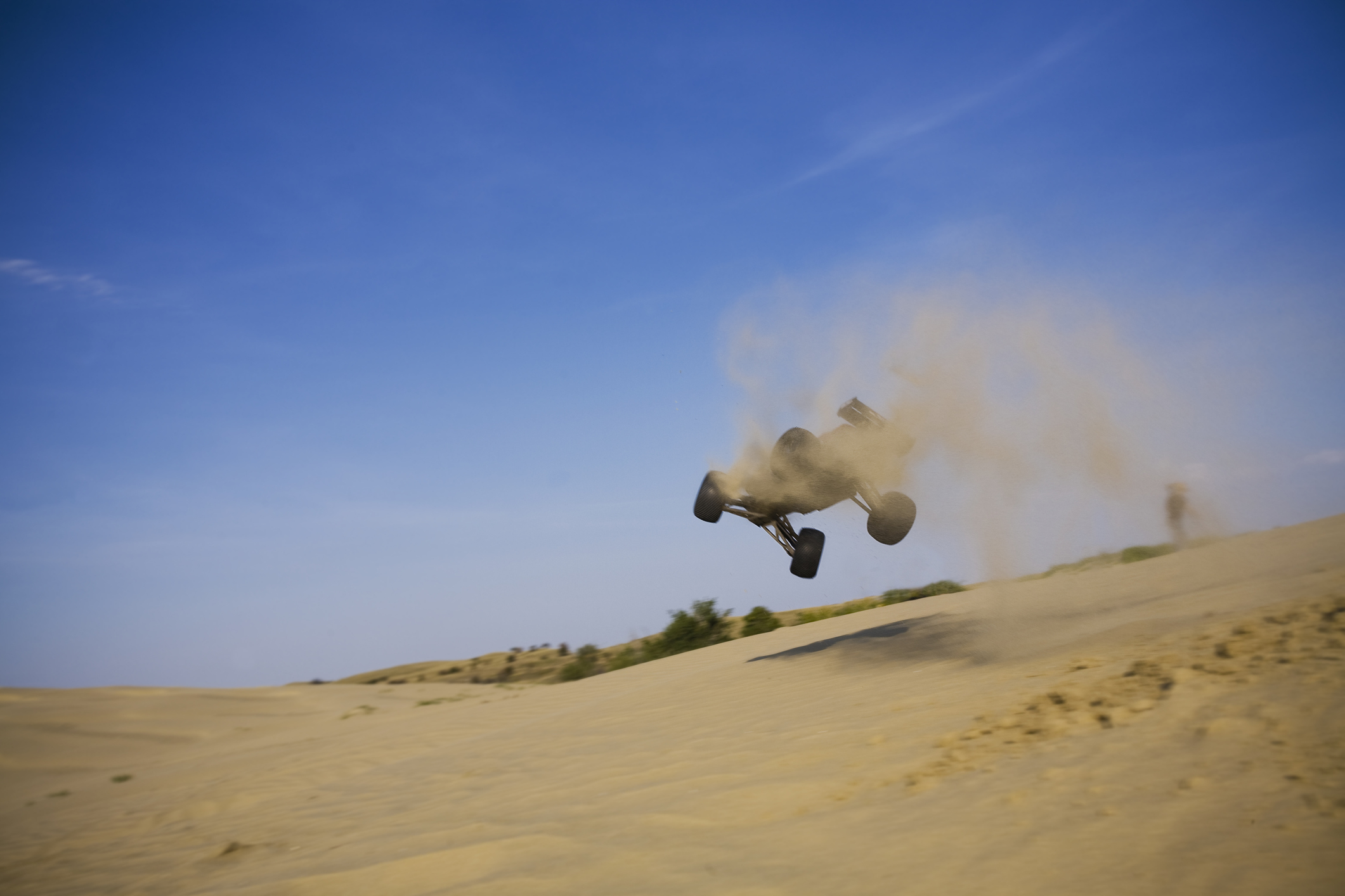 RC dune buggy going for a fly after hitting a sand jump.